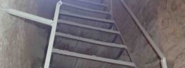 Bright light shining down a metal ladder from a tunnel