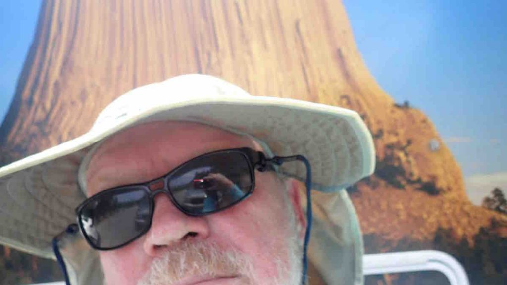 author standing in front of a picture of the Devil's Tower