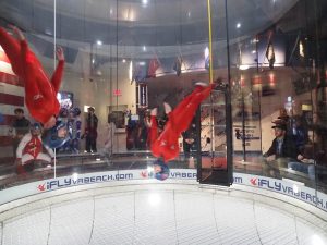 Two people flying upside down in a wind tunnel