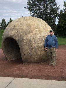 author standing by round sculpture with passageway through it
